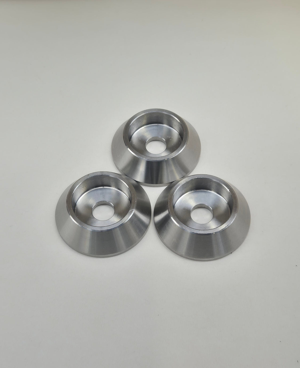 Three bolt head protectors arranged in a triangle showing recessed bolt seats and central holes