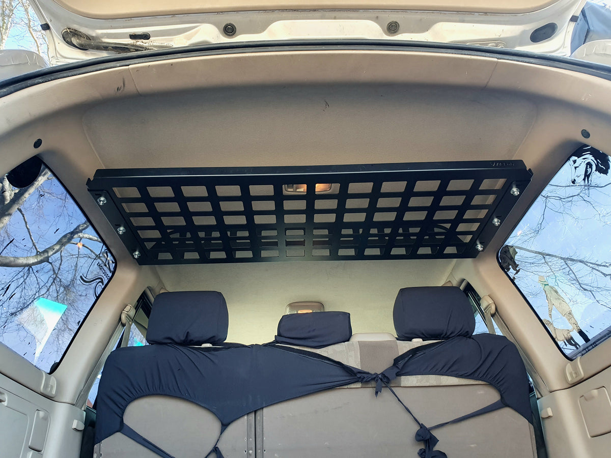 Straight rear view of Landcruiser 100 cargo shelf showing grid base and bolted side mounts