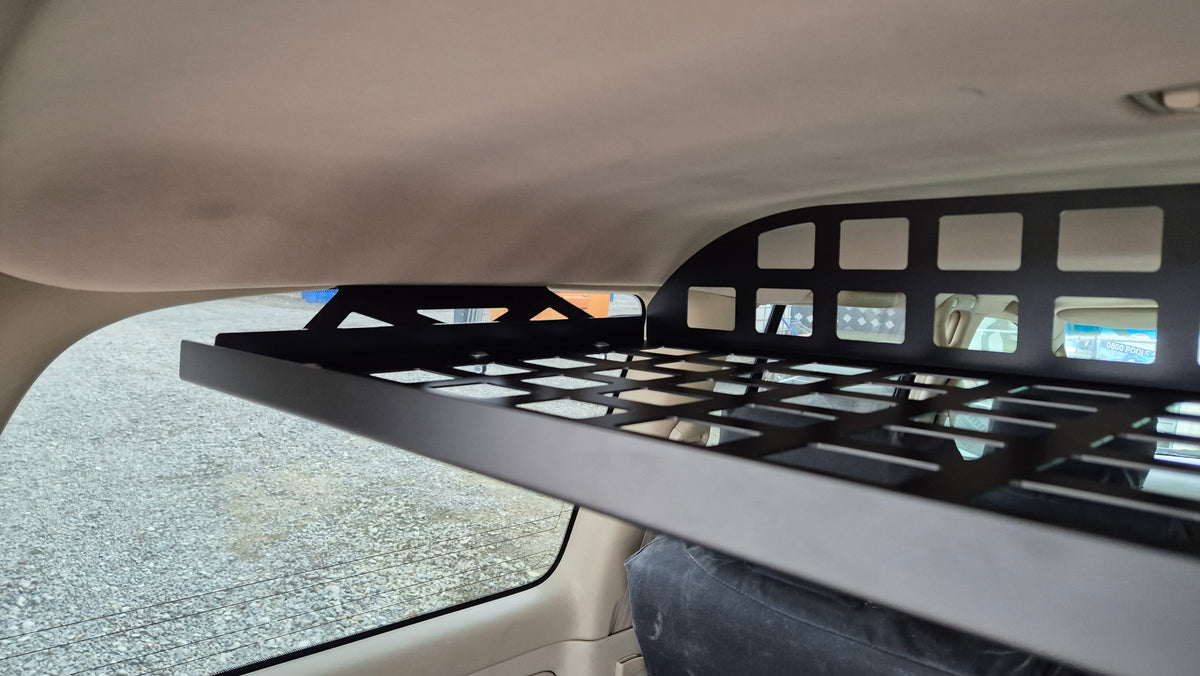 Side close-up of Landcruiser 100 cargo shelf showing grid base and raised retaining lip