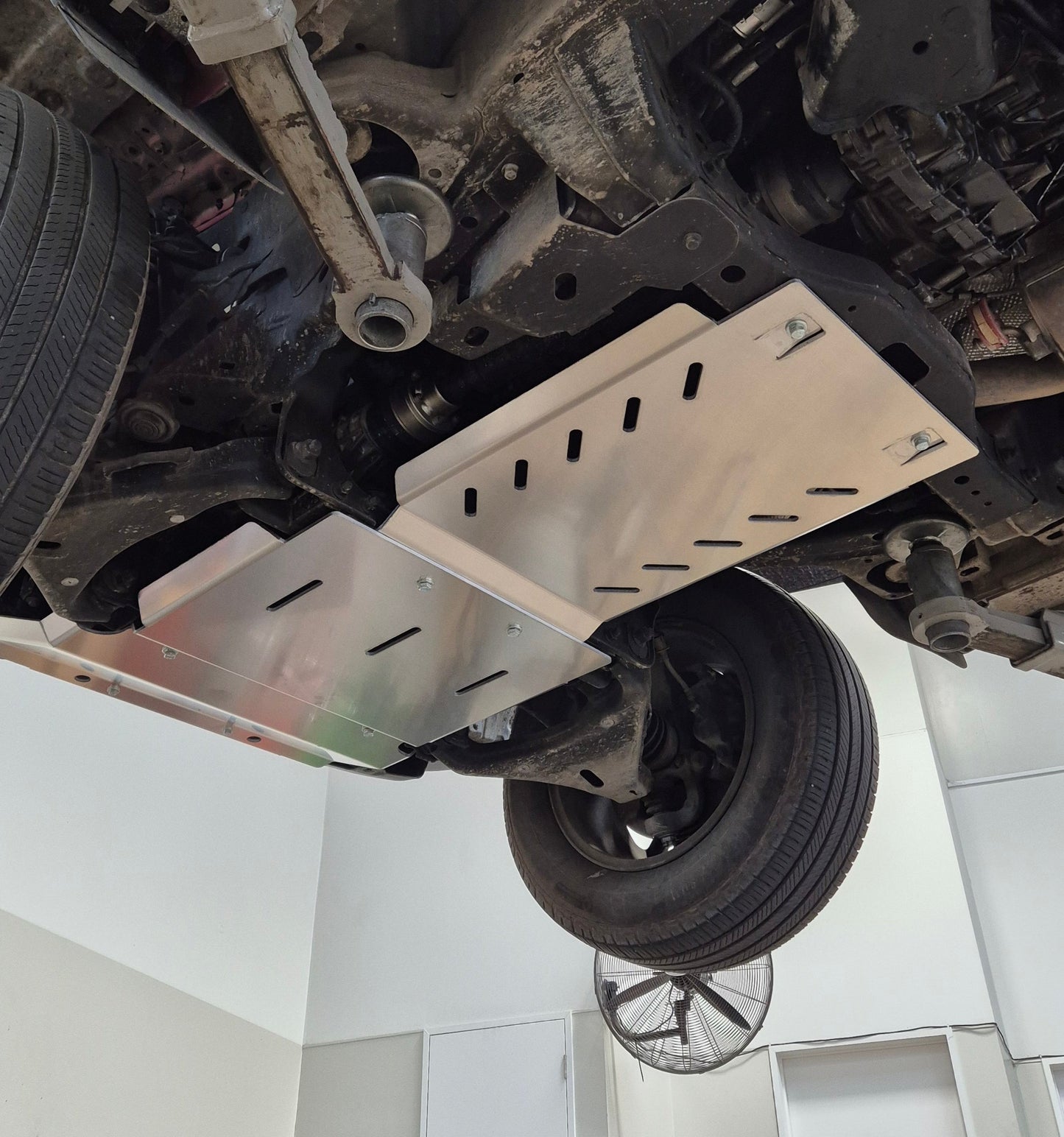 Undercarriage of a vehicle with a protective metal skid plate on a white background