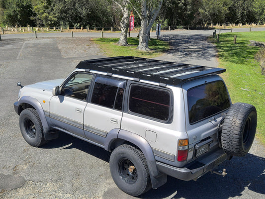 Elevated rear three-quarter view of Landcruiser 80 roof rack showing crossbars and gutter mounting brackets