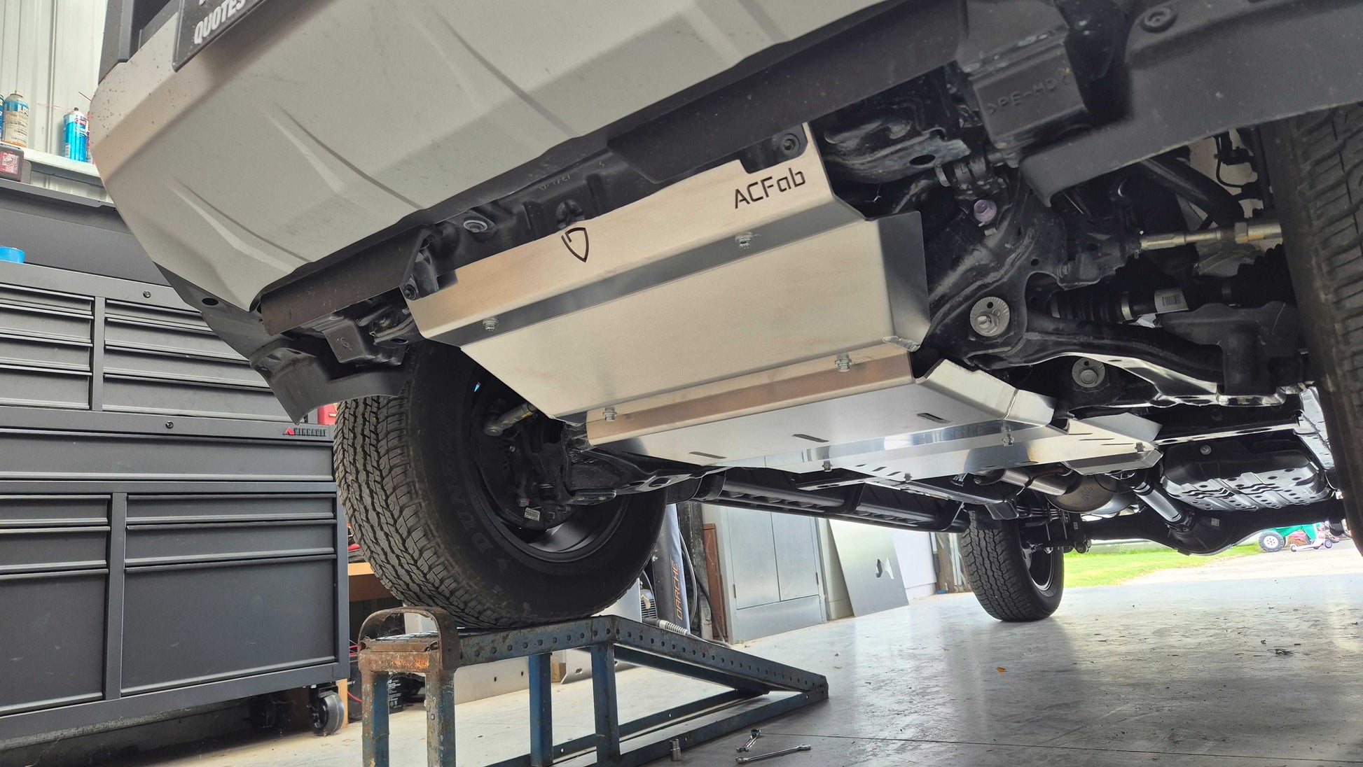 Undercarriage of a vehicle with a flatbed trailer attached, showing 'ACFab' branding.