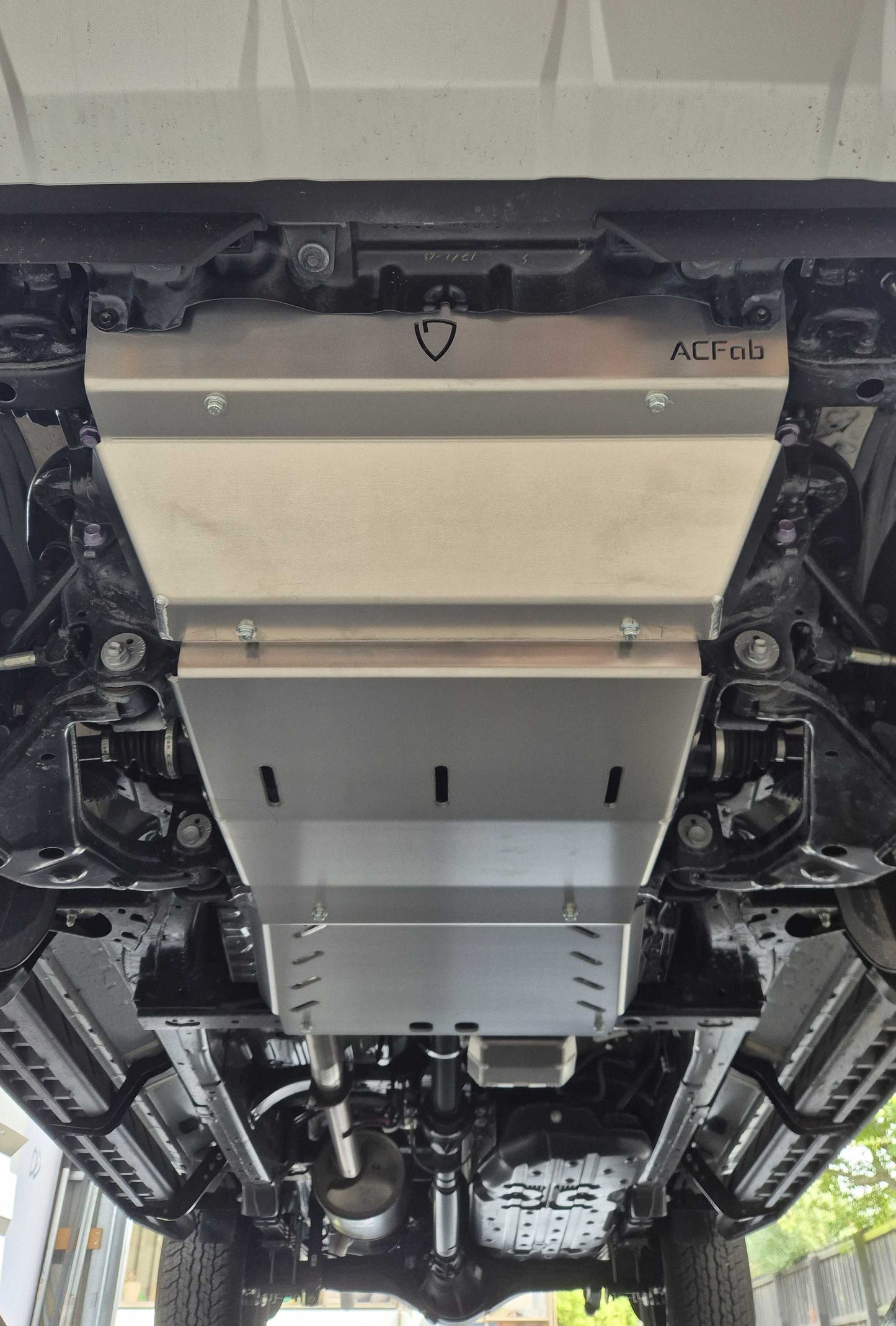 Metal undercarriage guard with ACFab branding on a vehicle.