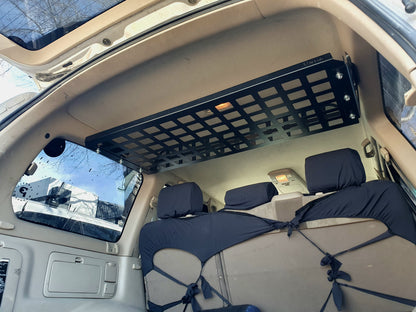 A black metal rear cargo shelf installed in the interior of a Toyota Landcruiser 100 series vehicle.