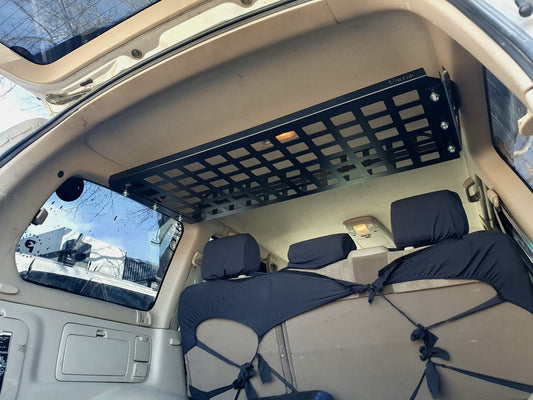 A black metal rear cargo shelf installed in the interior of a Toyota Landcruiser 100 series vehicle.